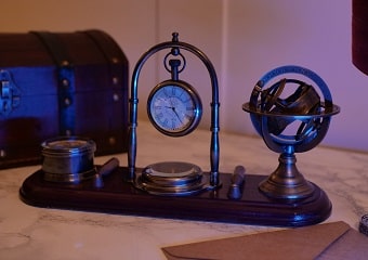 Une décoration de bureau composé d’une horloge, d’un globe et de boussoles